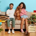 Pareja con perro rodeada de cajas de mudanza